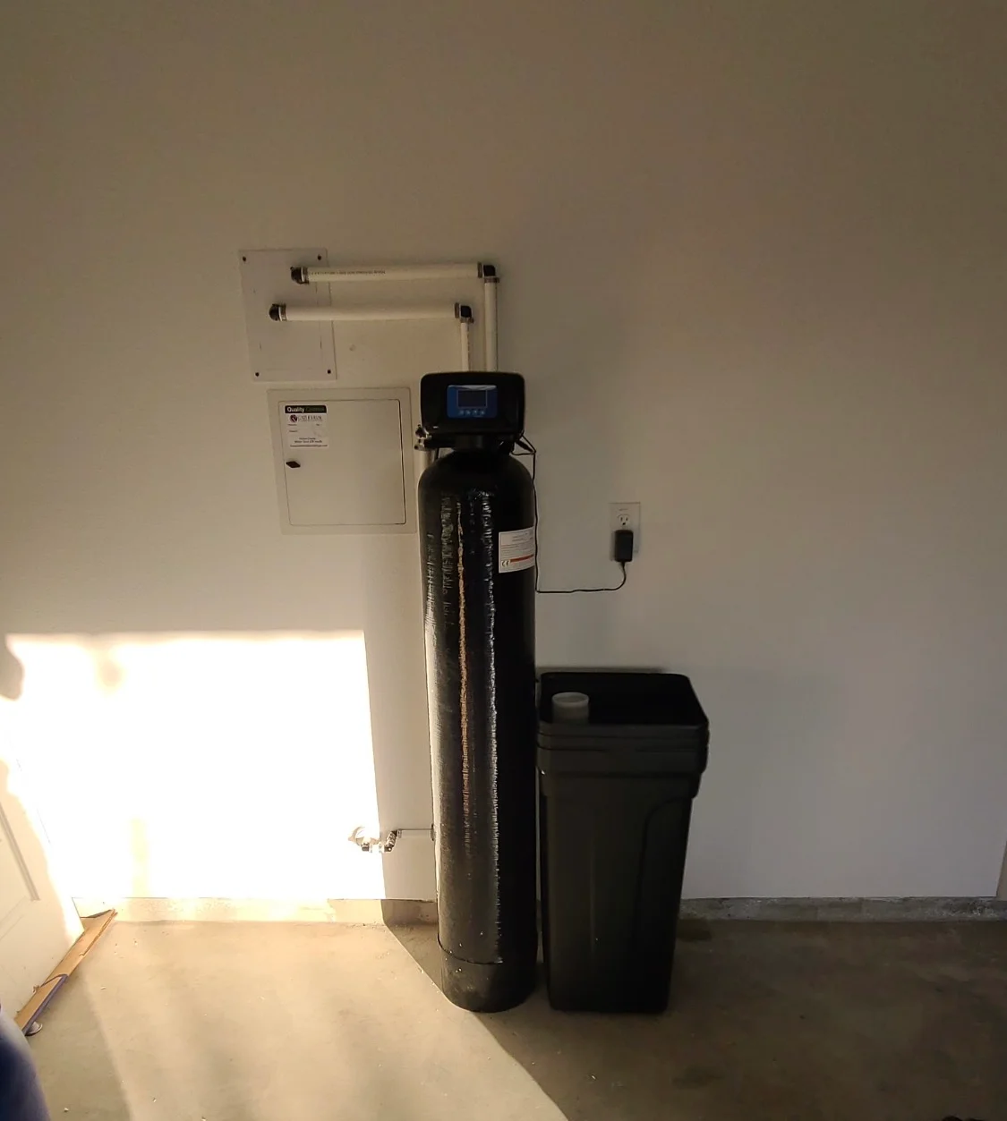 Installed water softener system with black resin tank and digital control display