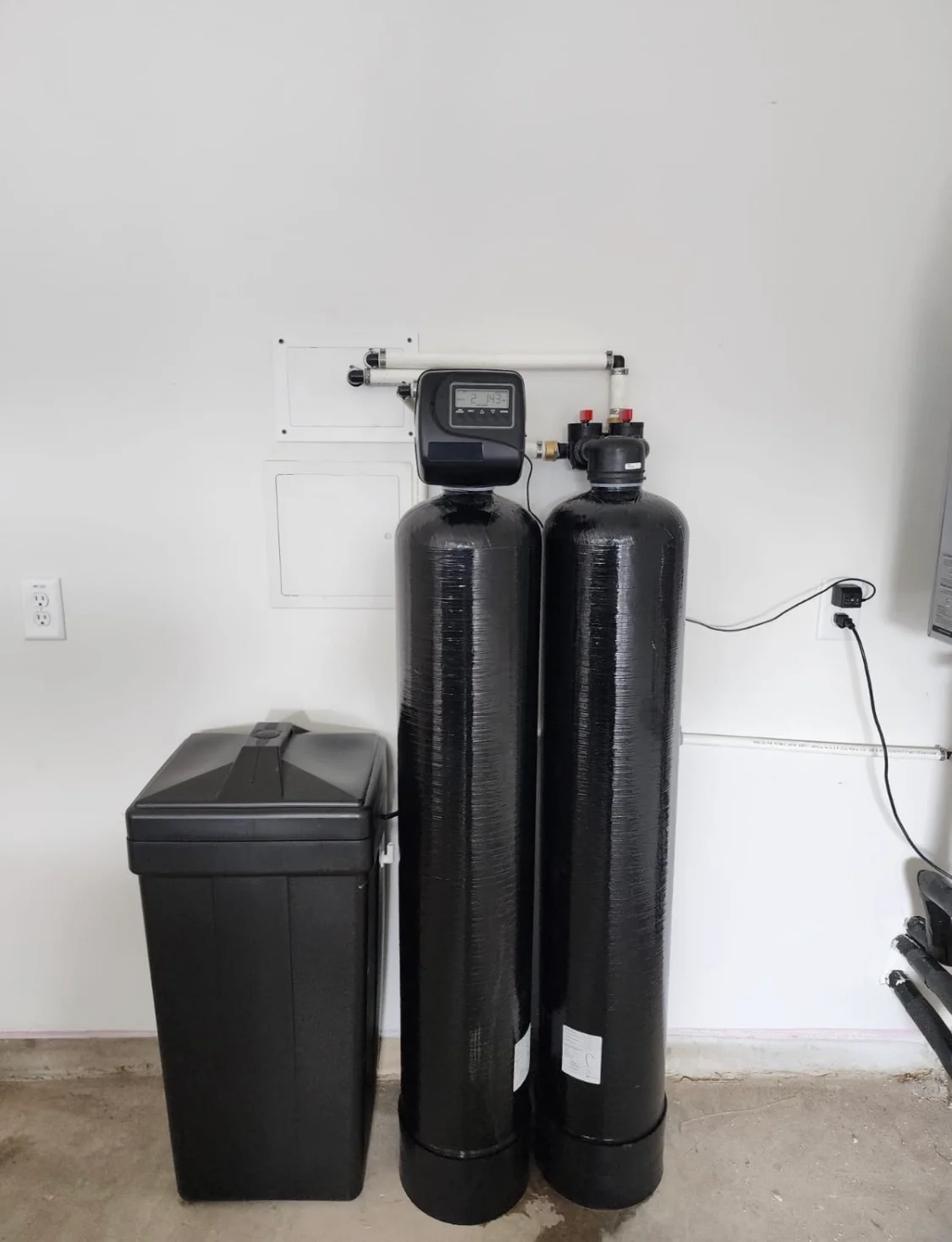 Dual-tank water softening system with digital meter and brine tank installed in basement Dual-tank water softening system with digital meter and brine tank installed in basement