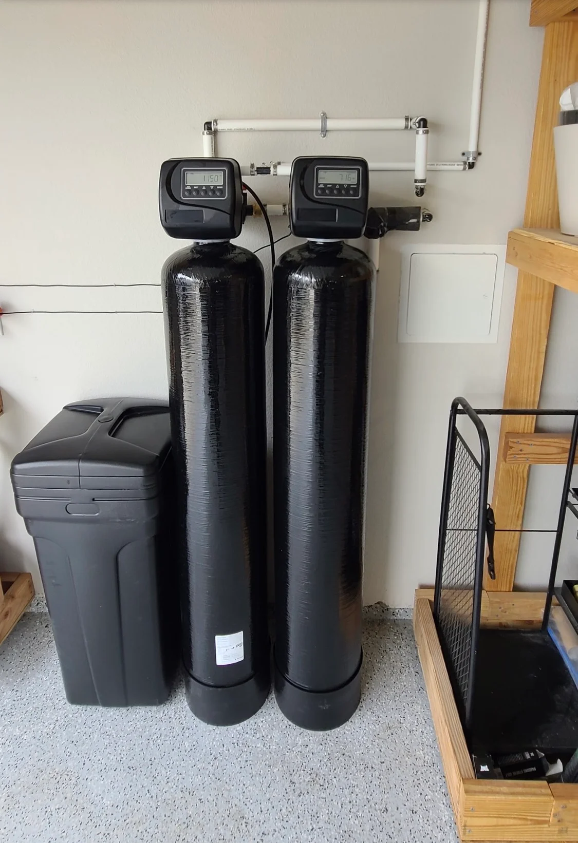 Dual black water softener tanks with digital controls and PVC piping installed in utility space