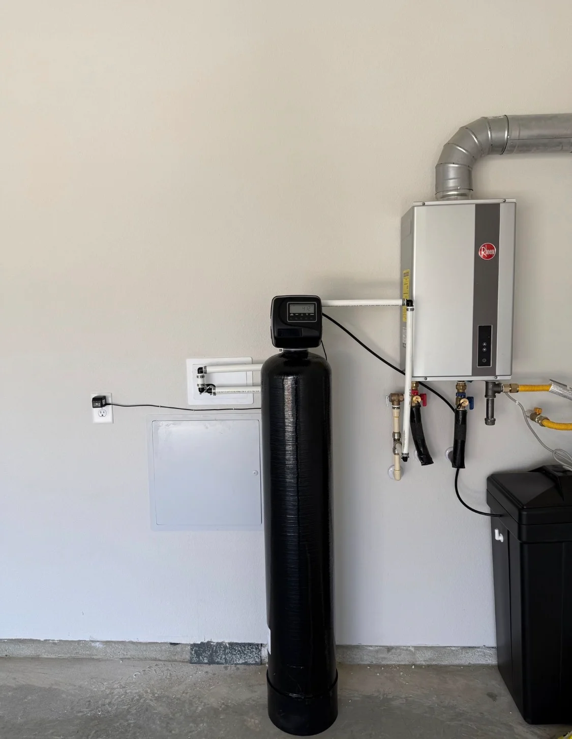 Installed whole-home water filtration system with softener tank and Rheem tankless heater