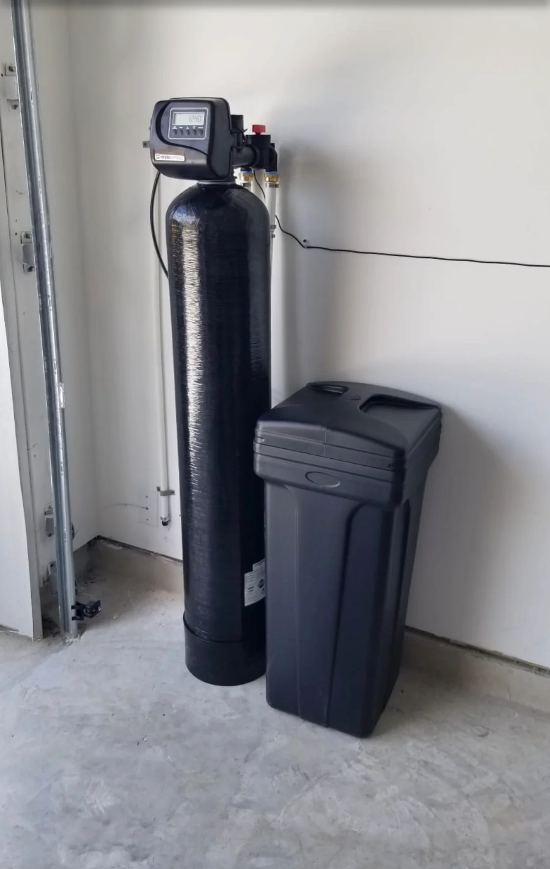 Black water softener and brine tank system installed in basement utility room